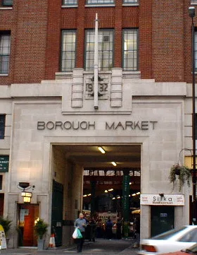 Drukke kraampjes van Borough Market onder de victoriaanse spoorwegbogen op London Bridge met bezoekers die proeven