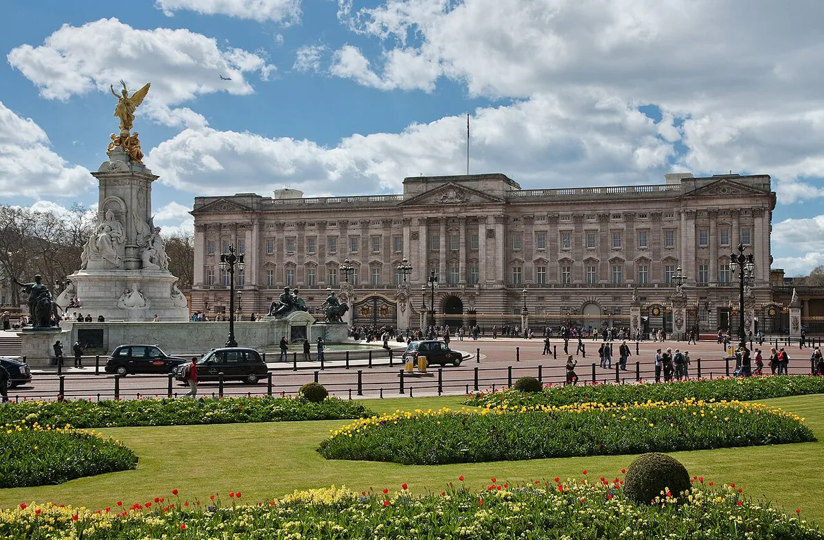 De voorgevel van Buckingham Palace met de Victoria Memorial op de voorgrond en de Union Jack op de mast