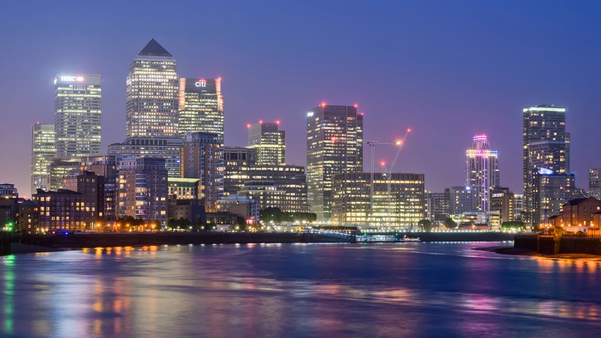 De glinsterende wolkenkrabbers van Canary Wharf weerspiegeld in het water van West India Dock bij avondschemering