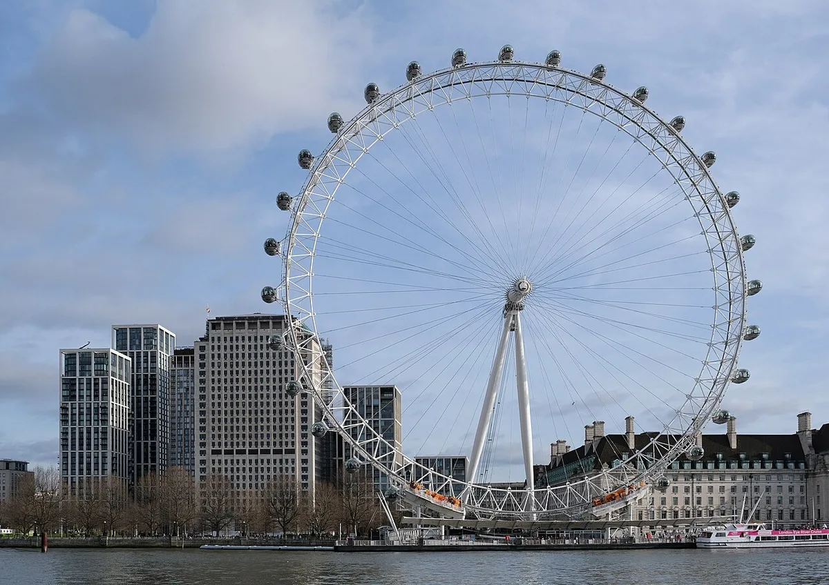 Het London Eye reuzenrad aan de zuidoever van de Thames weerspiegeld in het water bij zonsondergang