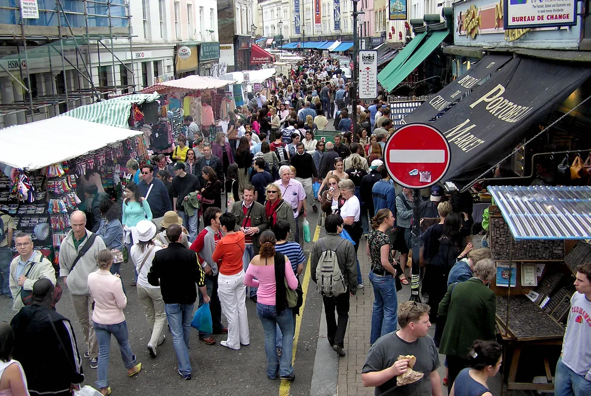 De kleurrijke pastelgevels en antieke stalletjes van Portobello Road in Notting Hill op een drukke zaterdag