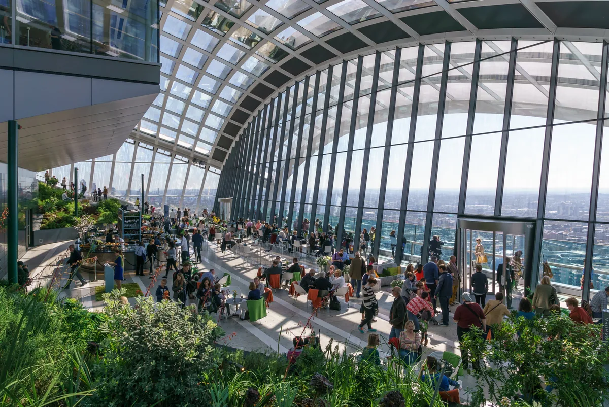 Het glazen dak van de Sky Garden in het Walkie Talkie-gebouw met tropische planten en uitzicht op de Londense skyline
